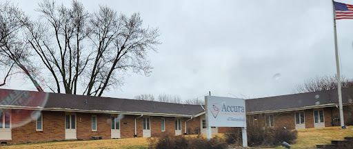 A view of a brick building with a sign for 'Acentra' against a cloudy backdrop.