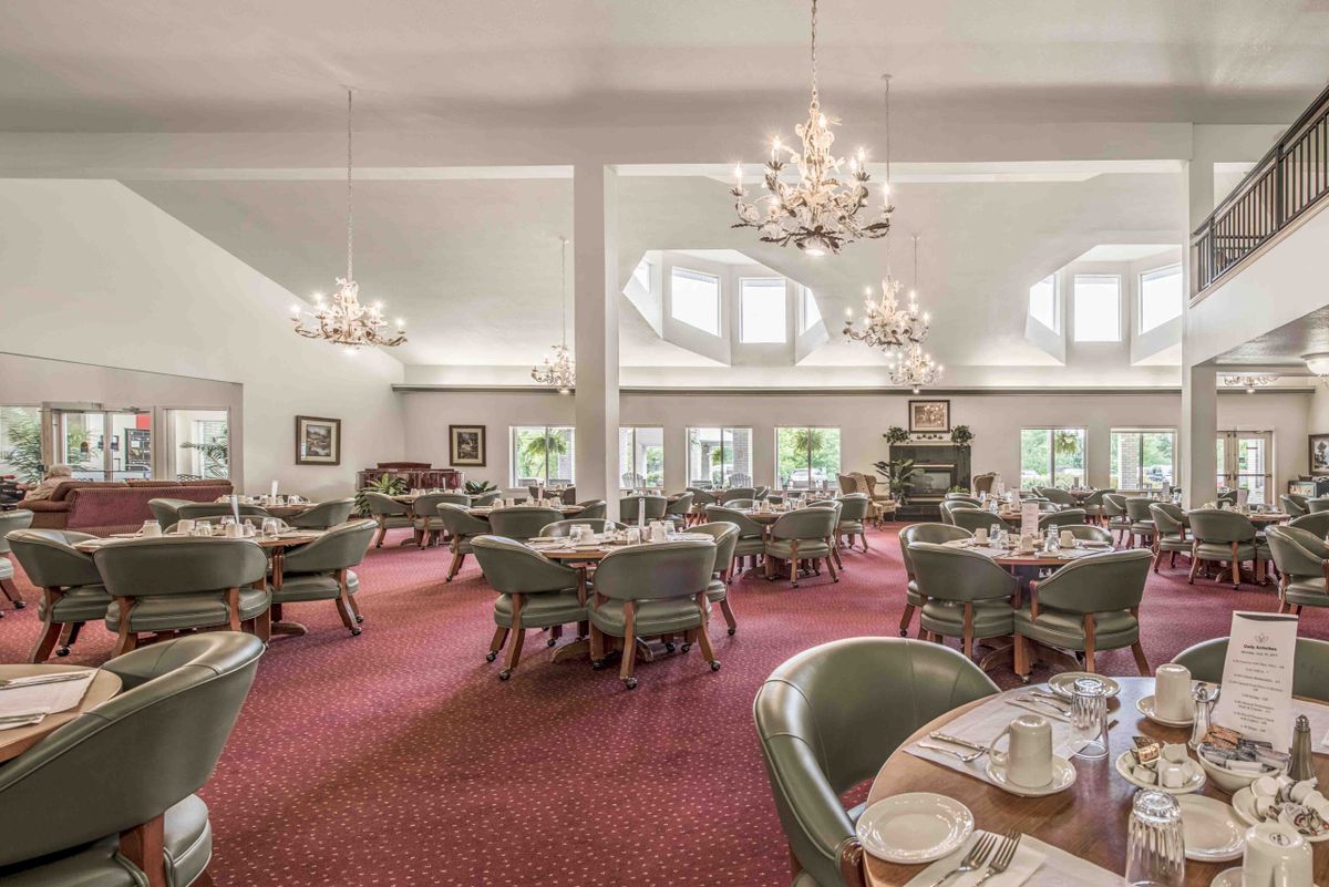 An elegant dining room with chandeliers, neatly arranged tables, and comfortable chairs.