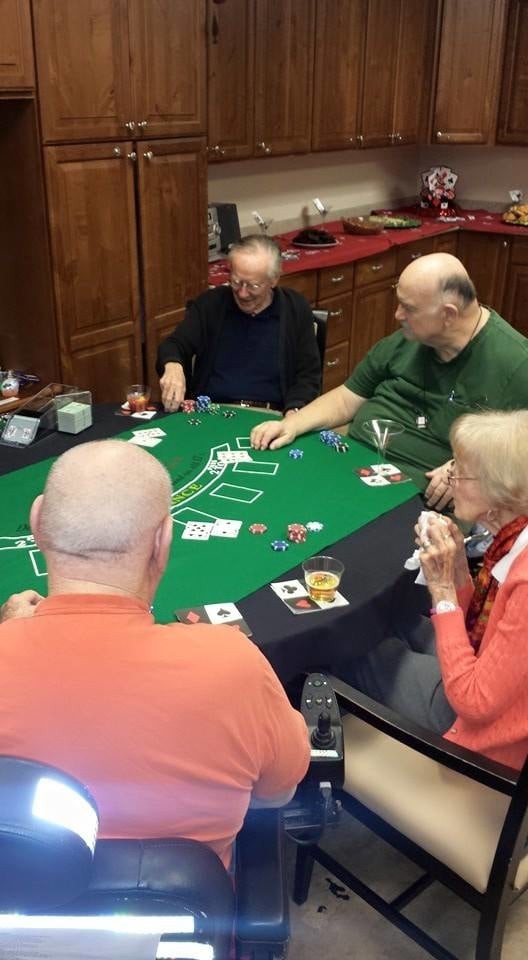 A group of adults playing poker around a table.