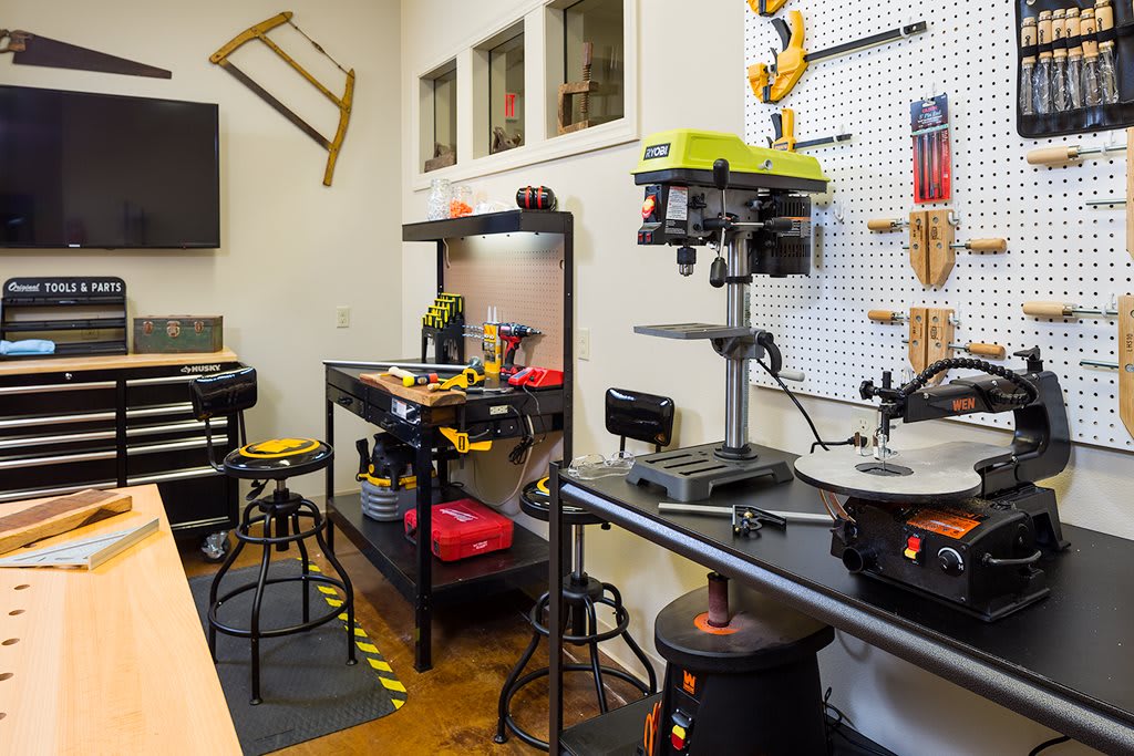 A well-organized workshop featuring various tools and machinery, including a drill press and workbenches.