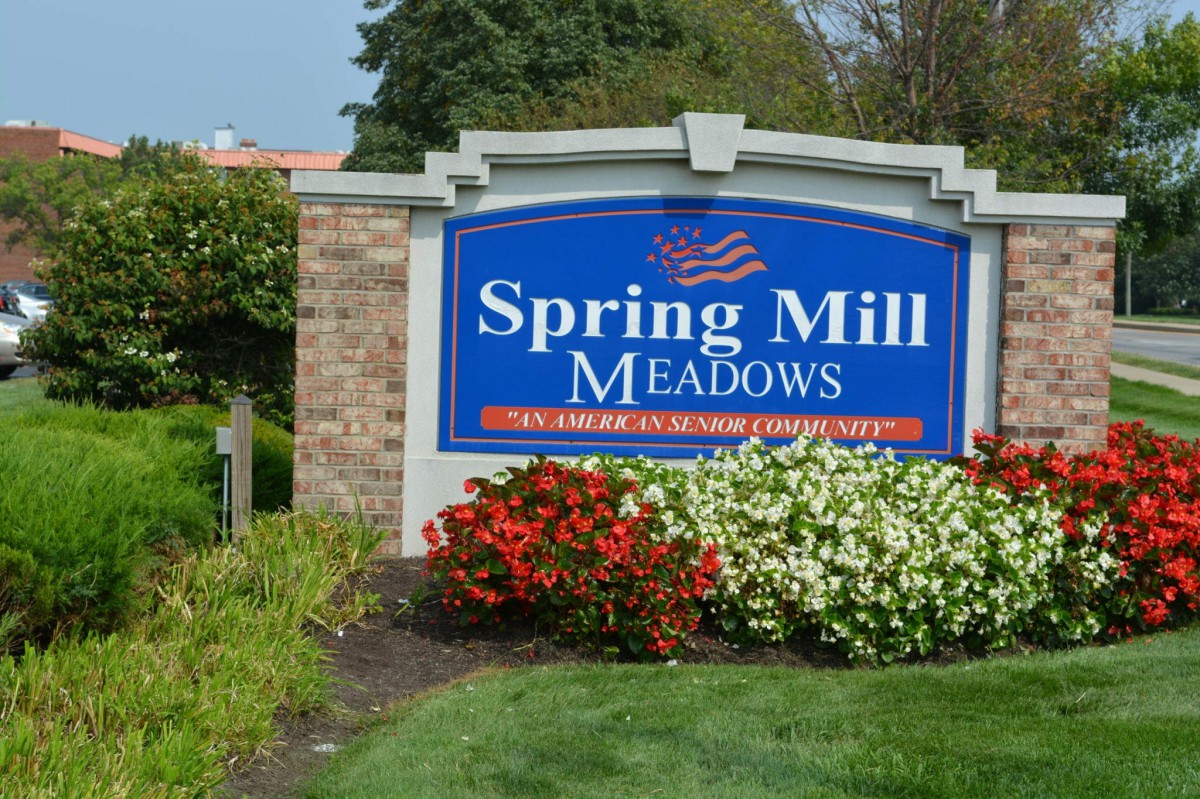 A landscaped entrance sign for Spring Mill Meadows surrounded by colorful flowers.