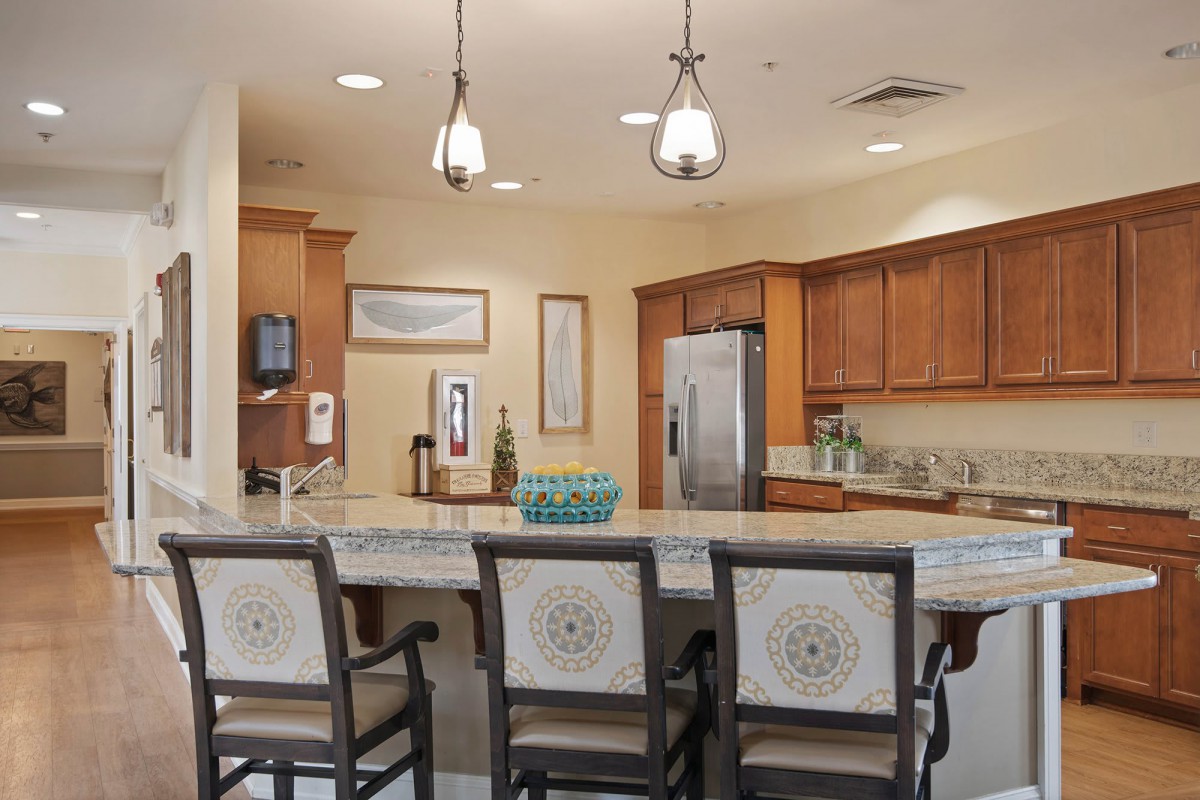 A modern kitchen interior with wooden cabinets, a spacious counter, and stylish pendant lights.