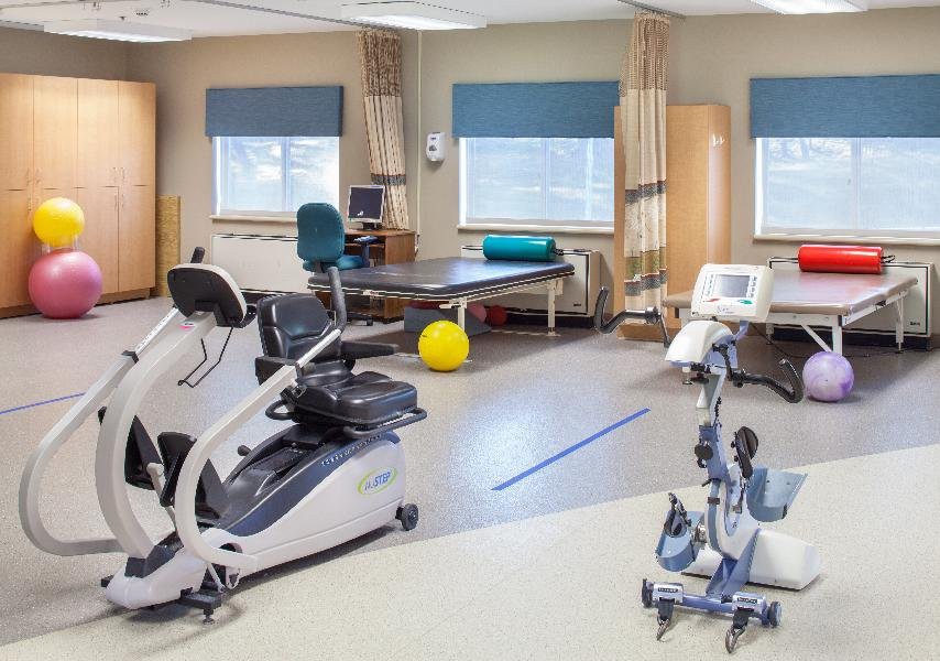 A physical therapy room equipped with various exercise machines and treatment tables.