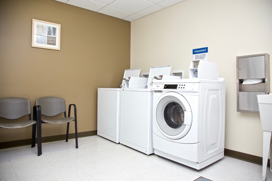 A clean laundry room with washing machines and a dryer.