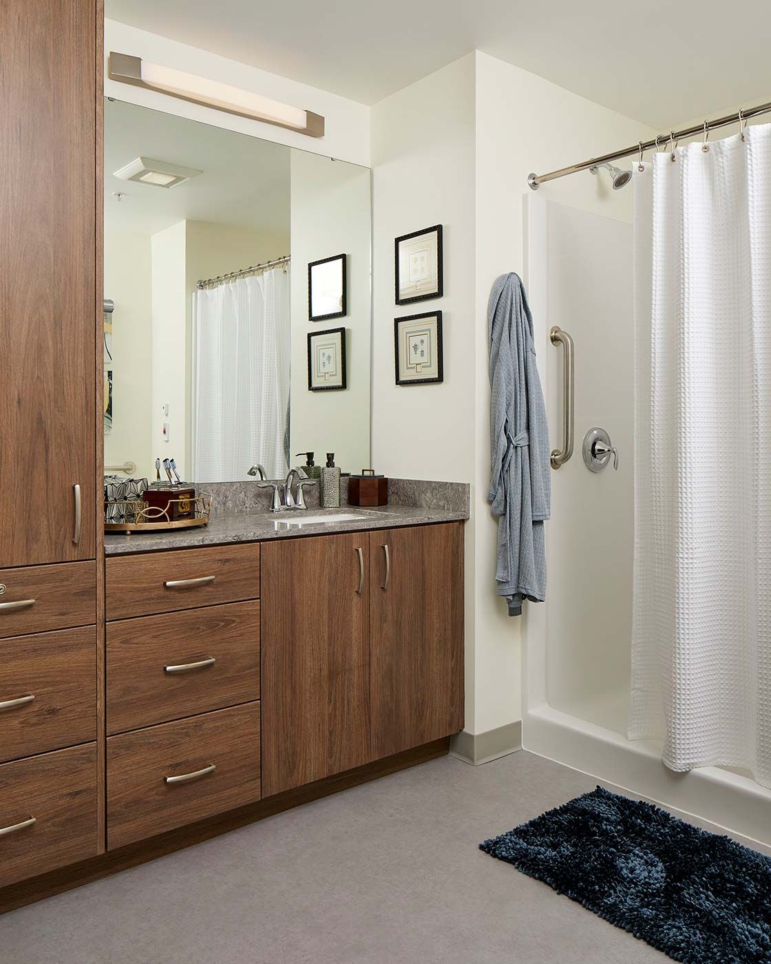 A modern bathroom featuring a shower with a curtain, a large mirror, and wooden cabinetry.