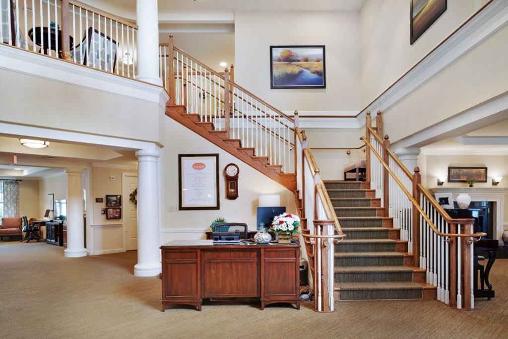 A spacious lobby with a central wooden staircase and reception desk.