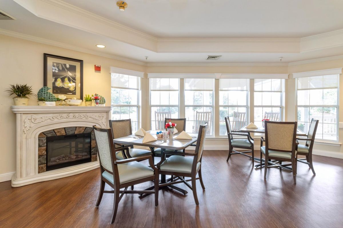 A cozy dining area featuring tables and chairs, with a fireplace and large windows providing ample natural light.