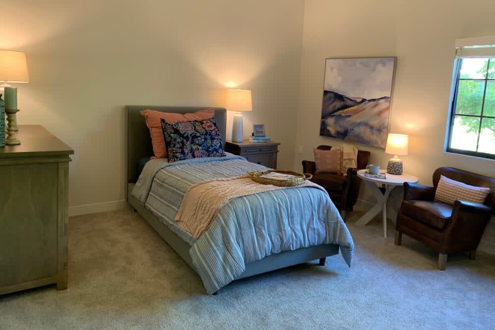 A cozy bedroom with a neatly made bed, two table lamps, and abstract artwork on the wall.