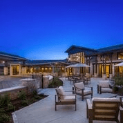 A modern outdoor patio area with chairs at dusk.