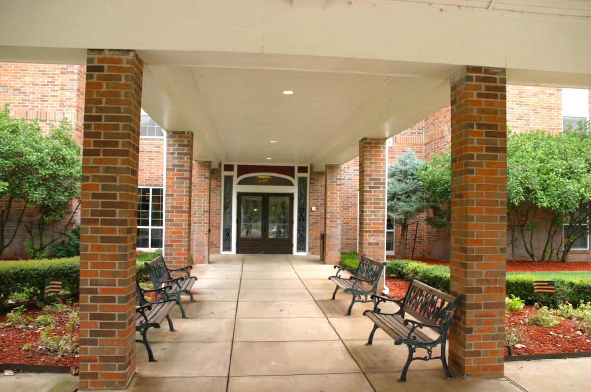 Brick building entrance with benches lining the pathway.