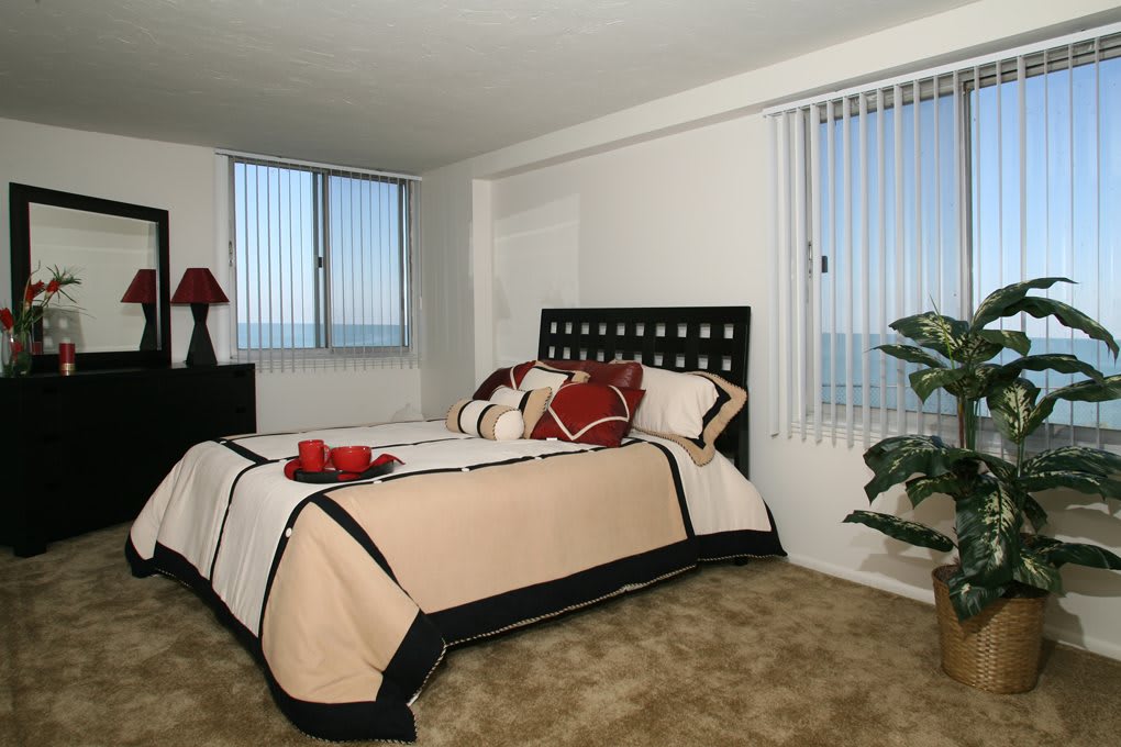 A modern bedroom with a neatly made bed and large windows.