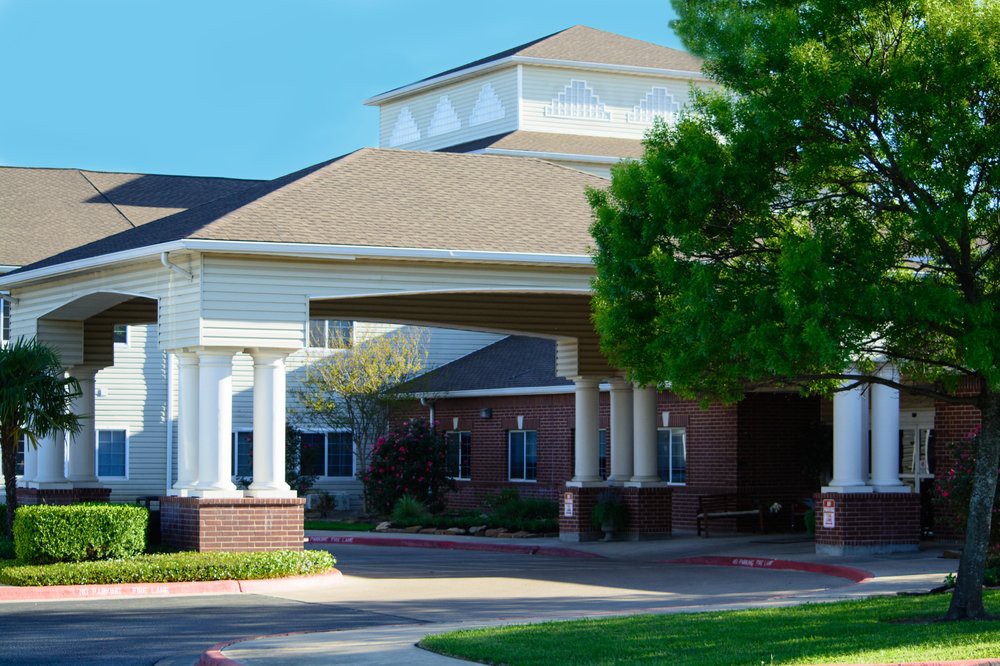 A front view of a building with a covered entrance and landscaped surroundings.