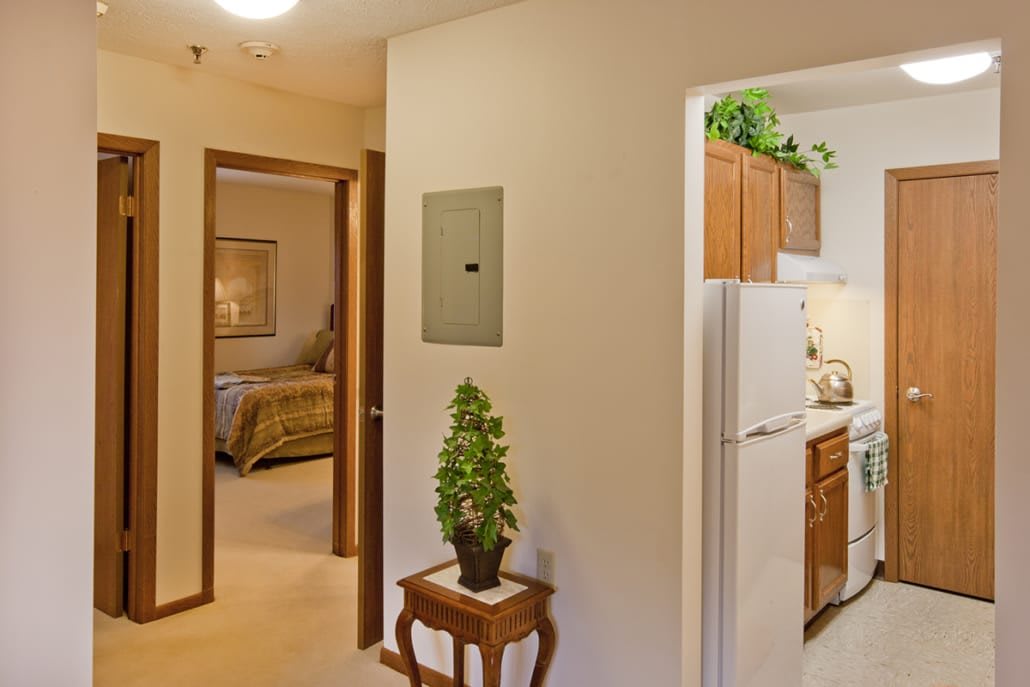 A view of a home interior showing a hallway leading to a bedroom and kitchen.