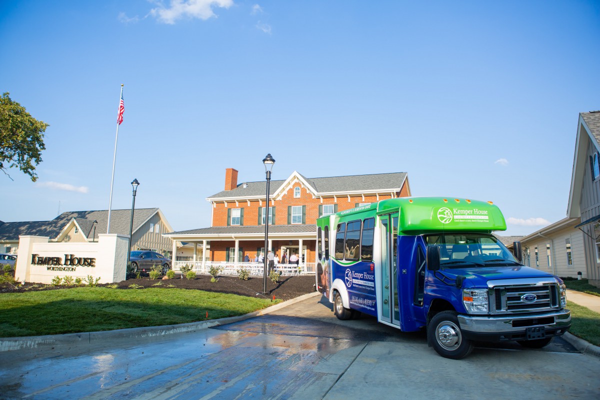 A shuttle bus parked in front of a brick building under a clear blue sky.