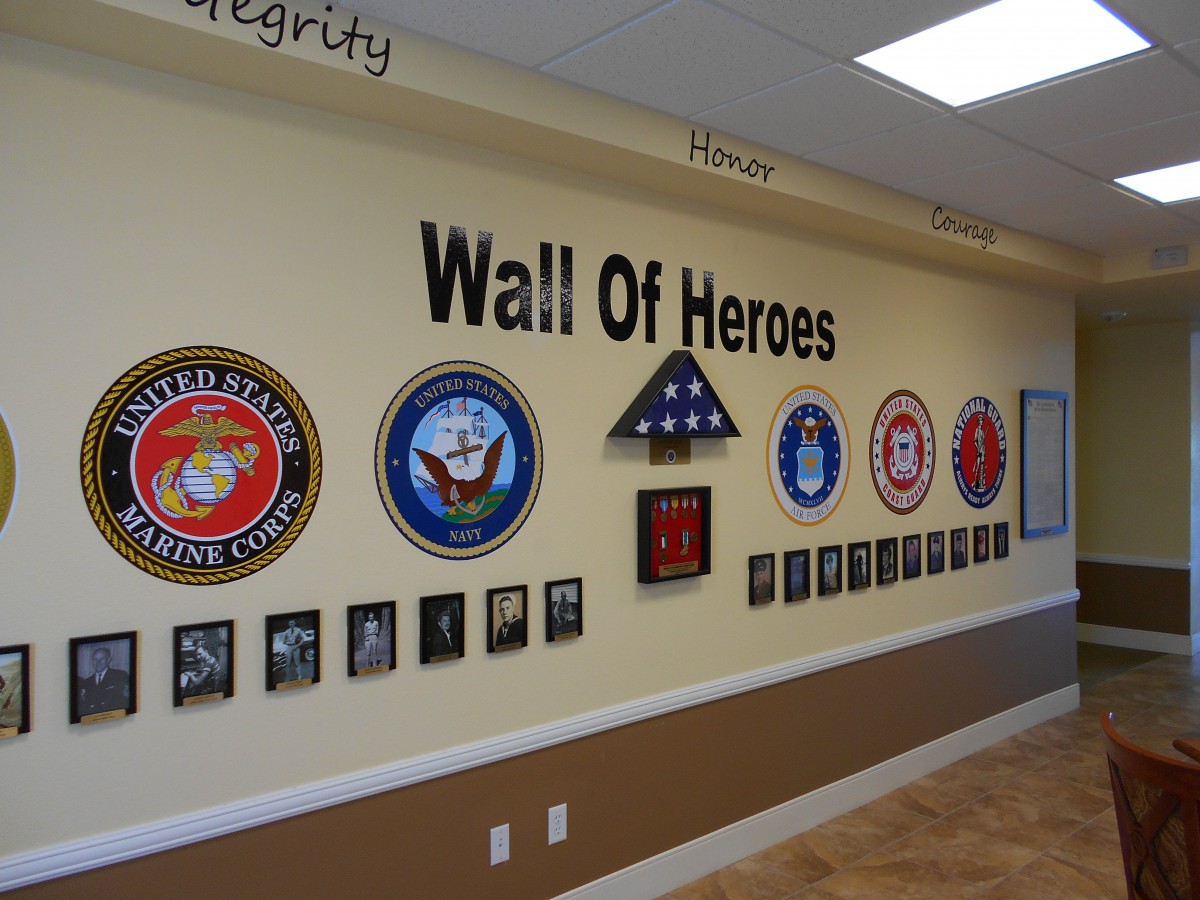 A Wall of Heroes dedicated to honoring military service members with plaques and service branch emblems.