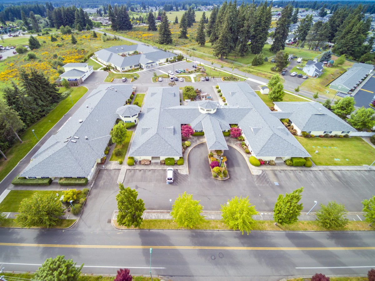 Aerial view of a building complex surrounded by greenery and a road.