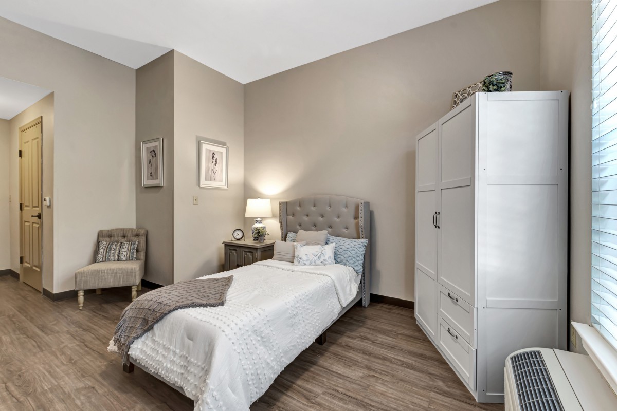 A modern and cozy bedroom with a single bed, nightstand with a lamp, and a stylish wardrobe in neutral tones.