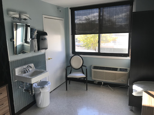 A clean and simple interior room with a chair, sink, and window.