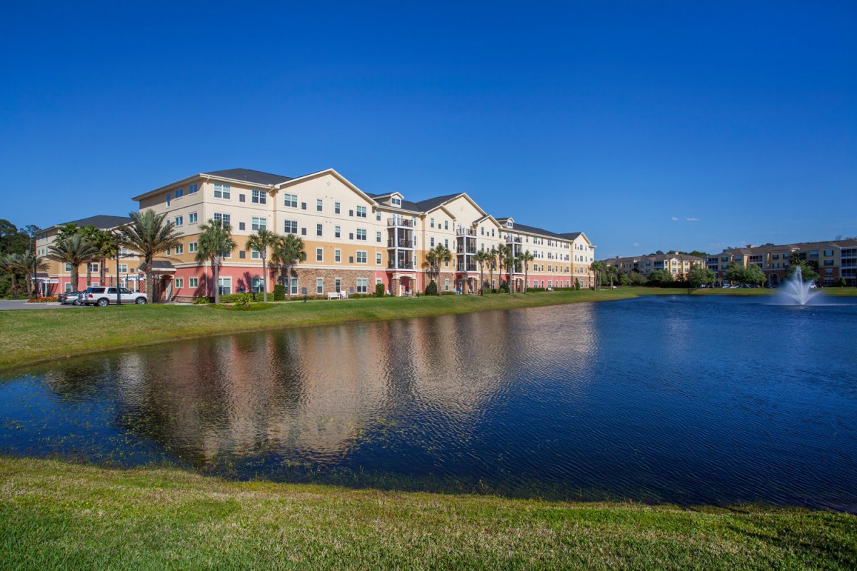 A view of an apartment complex with a lake and a clear blue sky.