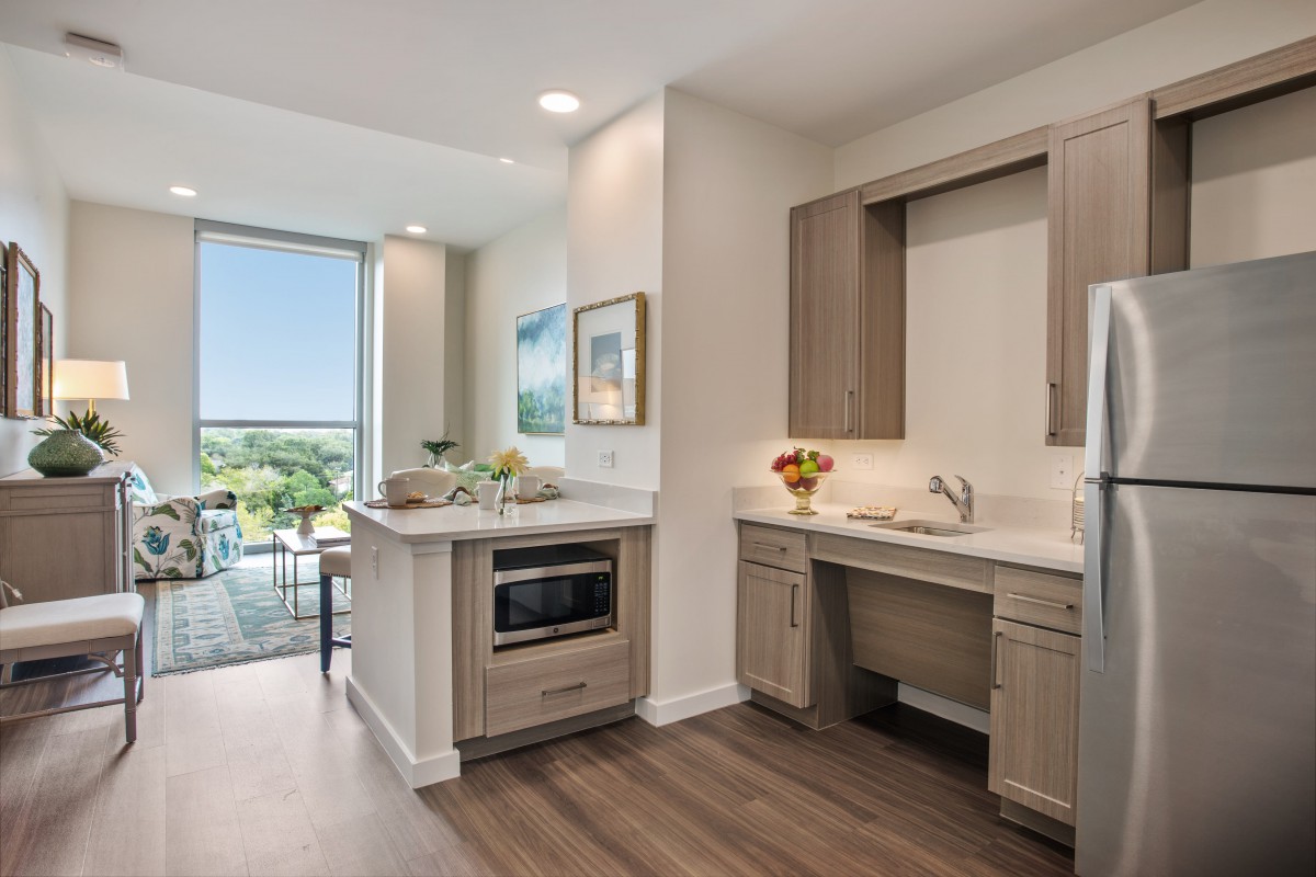 A modern, minimalist kitchen with wood flooring and a spacious, open layout.