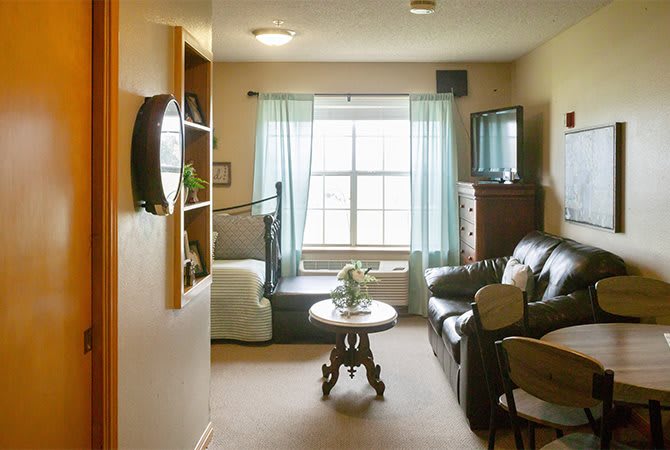 A cozy living room with a sofa, TV, and large window with curtains.