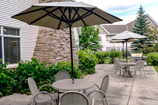 A serene outdoor seating area featuring tables with umbrellas surrounded by lush greenery.