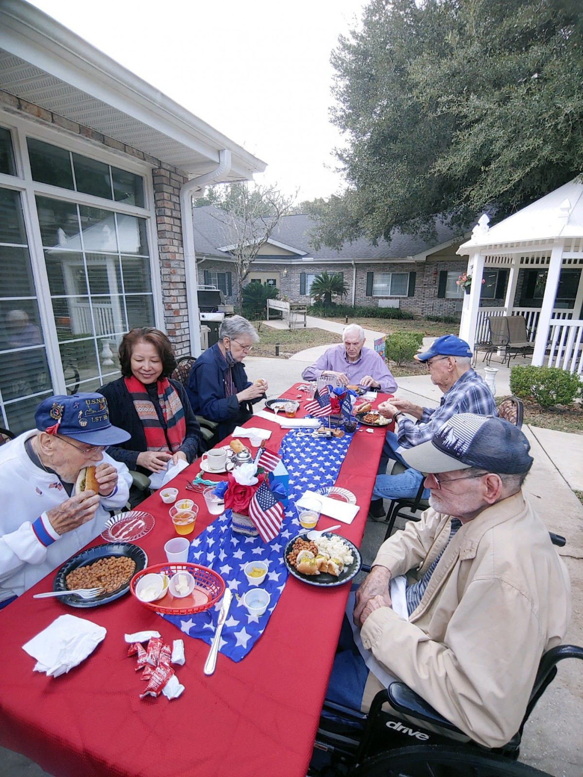 A group of people enjoying a meal at an outdoor gathering with a patriotic theme.