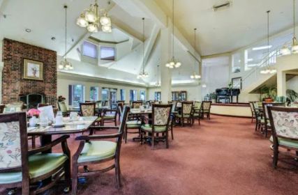 A spacious dining room with elegant chandeliers, large windows, and neatly arranged tables and chairs.