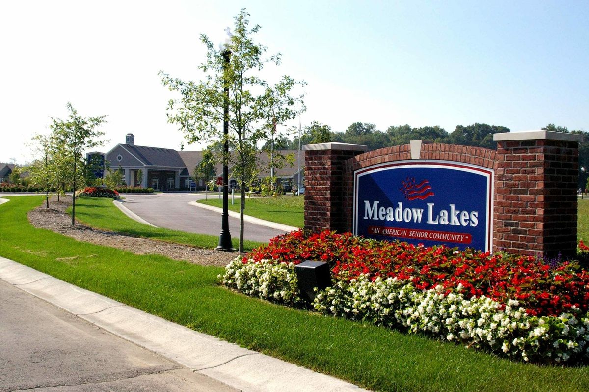 Entrance to Meadow Lakes residential community with a landscaped sign and surrounding greenery.