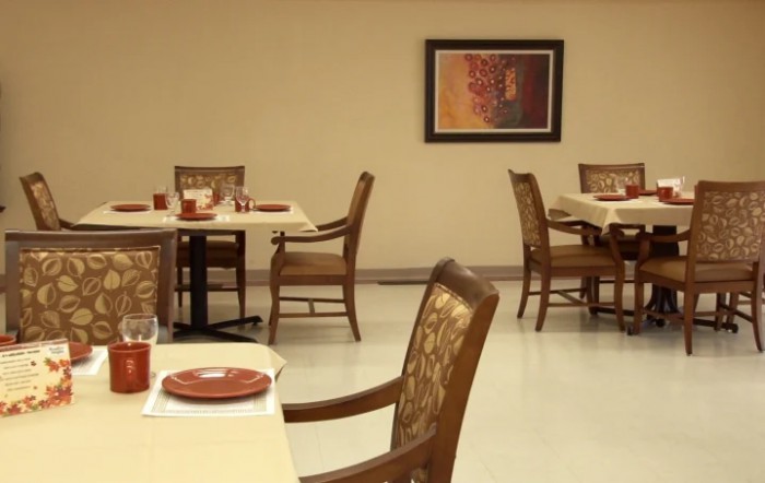 An empty dining area with neatly arranged tables and chairs, featuring artwork on the wall.
