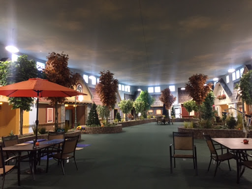 A cozy indoor shopping area featuring decorative trees and seating arrangements under a softly lit ceiling.