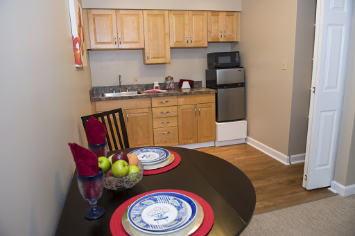 A cozy kitchen featuring wooden cabinets and a small dining area with a table set for two, complete with fresh fruits.
