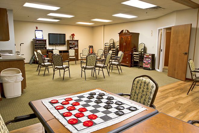 A recreation room with a checkers board in the foreground and seating arranged for group activities.