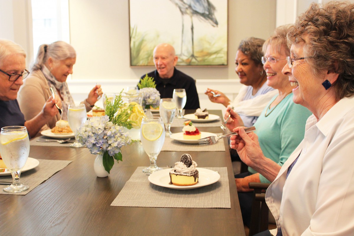 A group of seniors enjoying dessert together at a dining table.