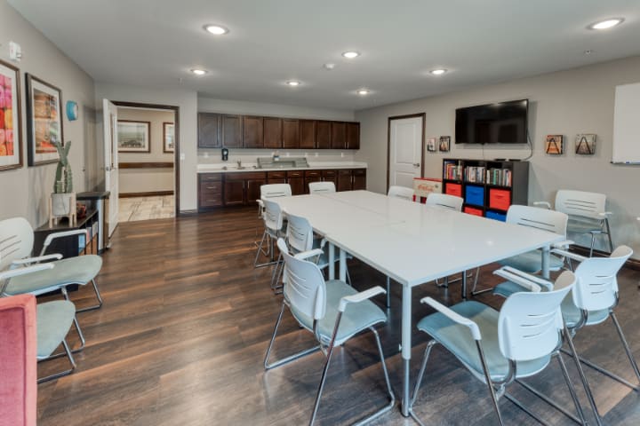 A modern conference room with a large table, chairs, and a television on the wall.