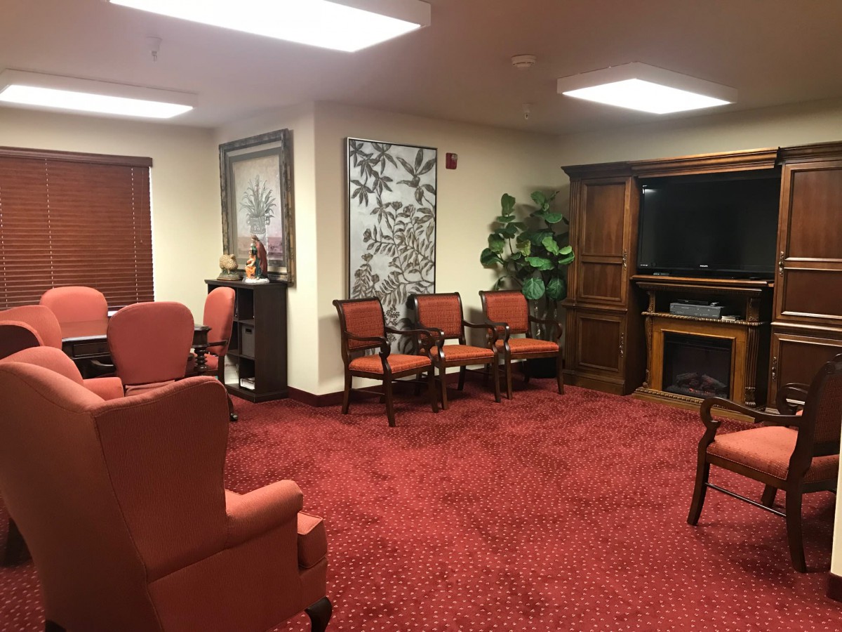This image depicts a waiting room with red carpeting, comfortable chairs, and a television.