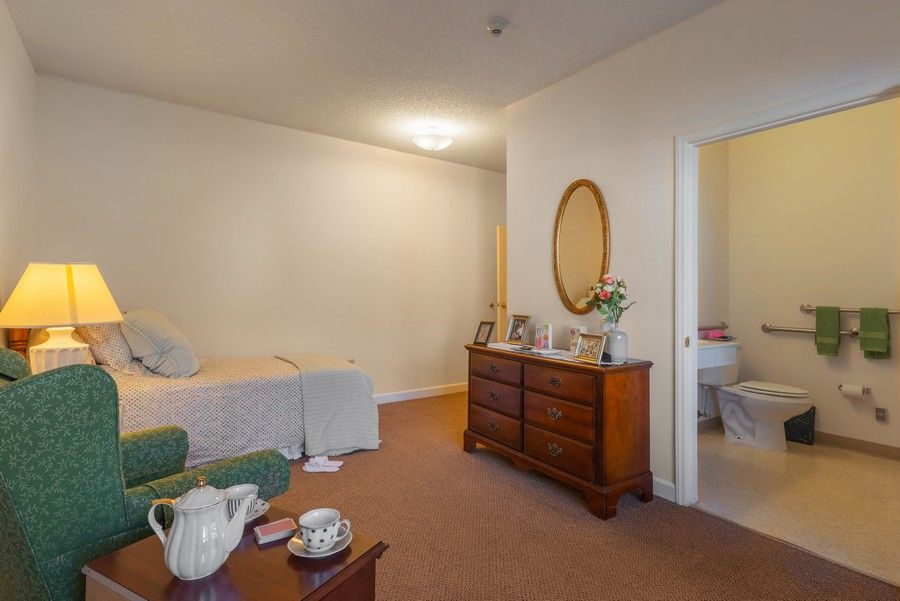 A cozy bedroom with a bed, dresser, and mirror, featuring simple decor.