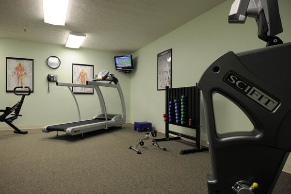 A small gym with a treadmill, weights, and exercise equipment.
