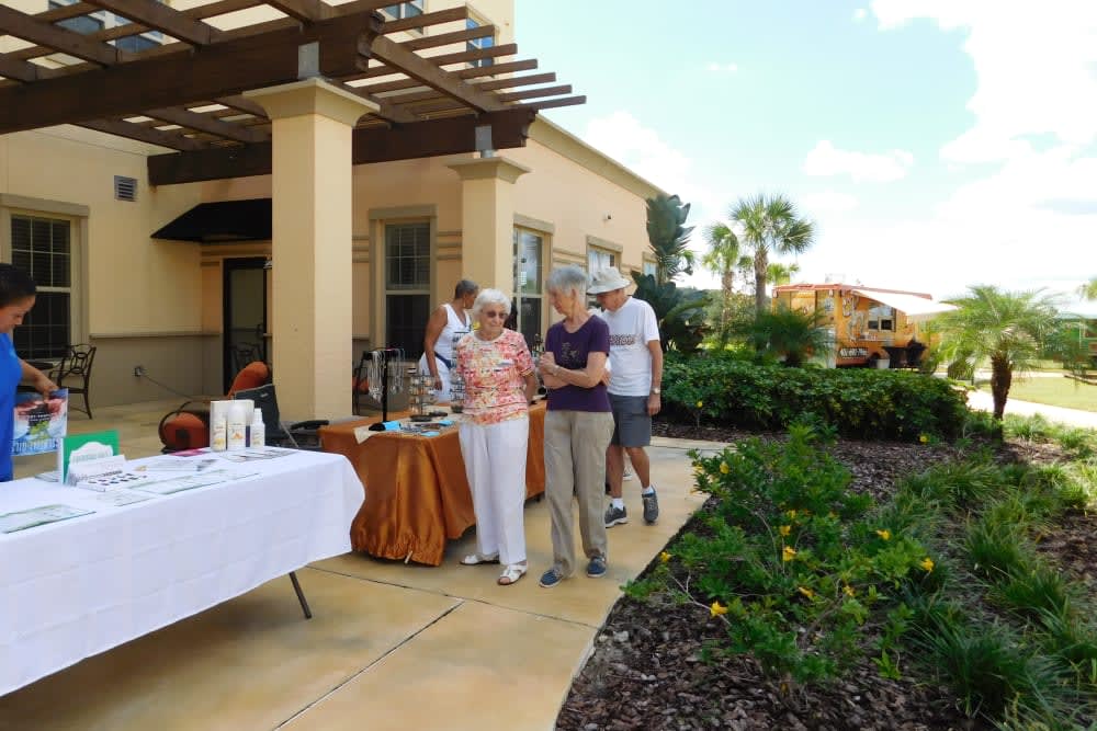 A group of people enjoying an outdoor social gathering on a patio surrounded by a garden.