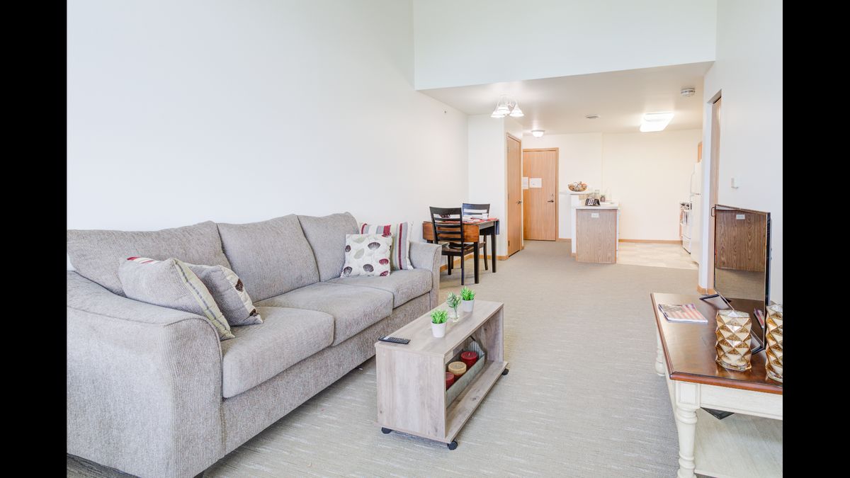 A modern living room with a cozy sofa and coffee table, adjacent to a dining area.