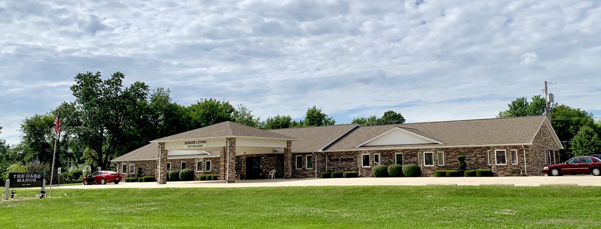 A stone building surrounded by green grass and trees under a cloudy sky.