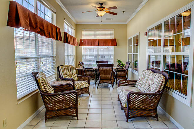A bright sunroom with wicker furniture and large windows allowing natural light to fill the space.