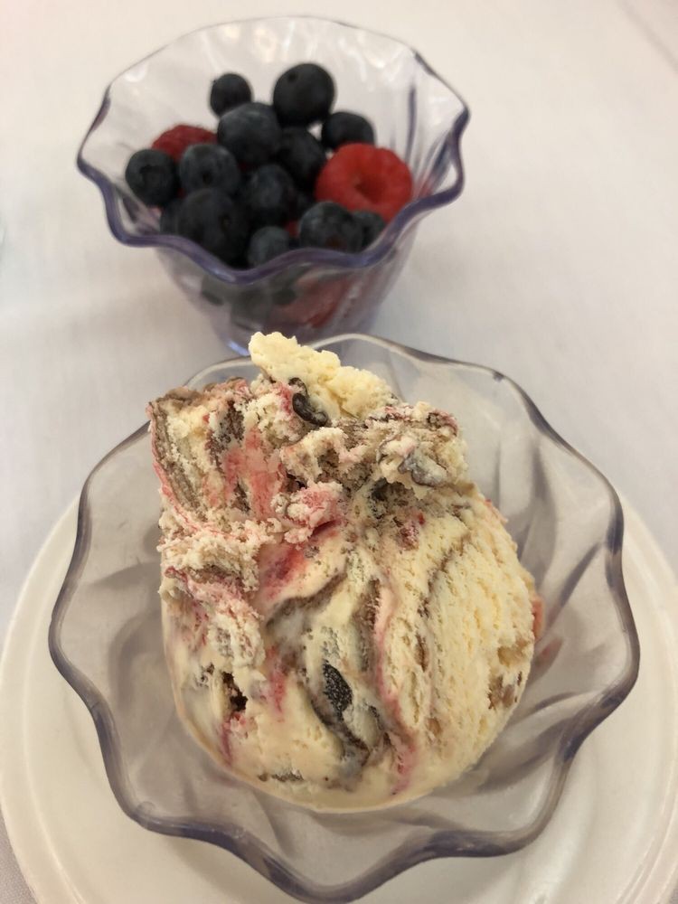 A bowl of ice cream with a side of fresh berries.