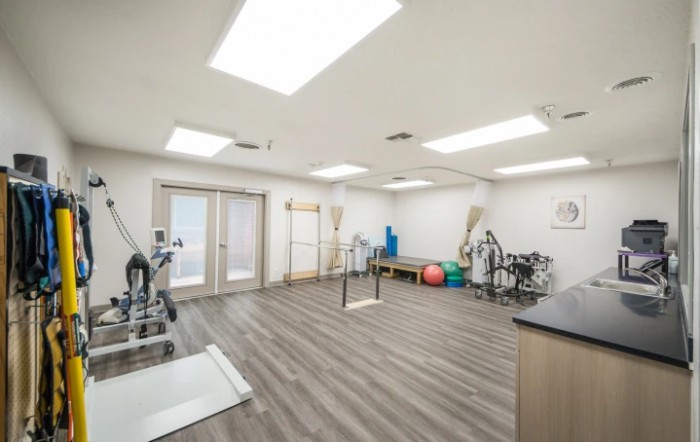 A well-lit gym space equipped with various exercise and rehabilitation equipment.