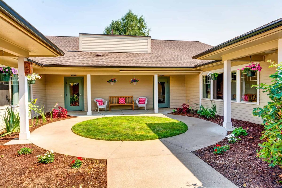 A serene courtyard with a circular lawn, surrounded by a patio and suburban house architecture.