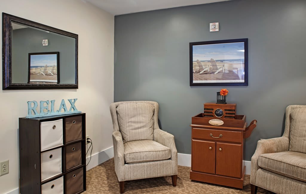 A cozy living room corner with an armchair and cabinet, decorated for relaxation.