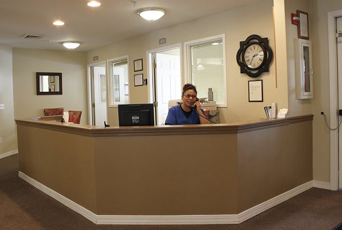 A receptionist answering a phone call at an office desk.