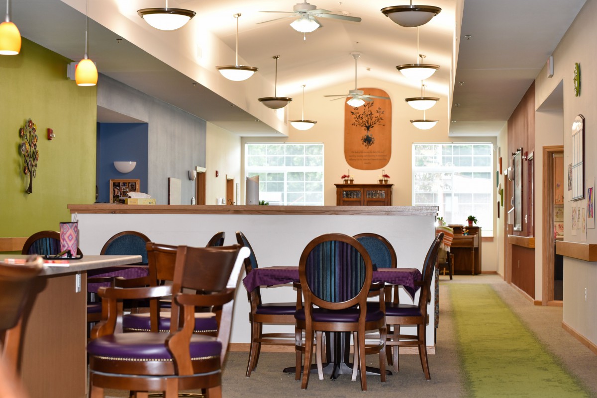 A well-lit dining area featuring wooden tables and chairs with a carpeted floor.