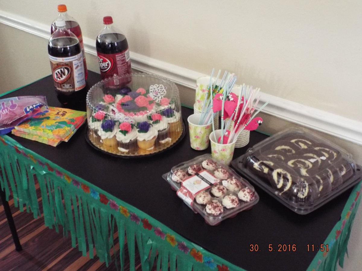 A table set for a party featuring a variety of cupcakes, drinks, and snacks.