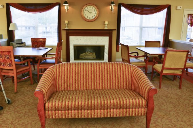 A cozy living room with a striped sofa, fireplace, and decorative clock.